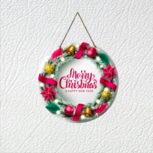 Round holiday wall hanging measuring 10x9 inches, featuring a printed wreath design with pine needles, gold bells, red ribbons, and pink poinsettias. The text in the center reads "Merry Christmas & Happy New Year" in red cursive font.